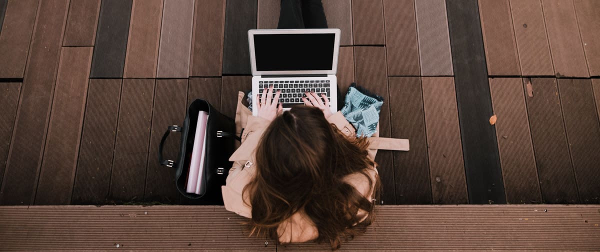 Young woman sitting on public park with laptop