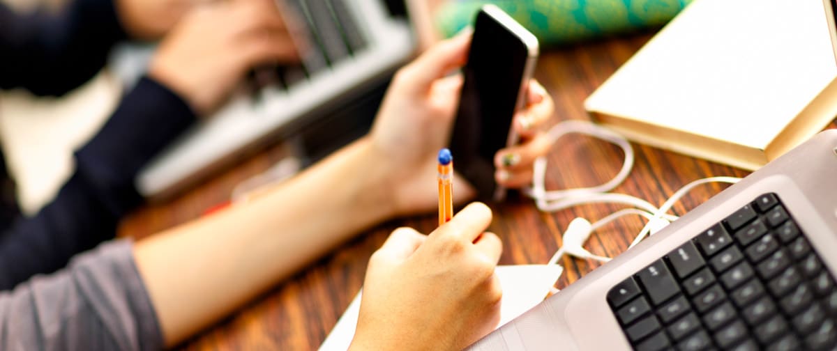 Female students hands working with laptop and cellphone in classrroom