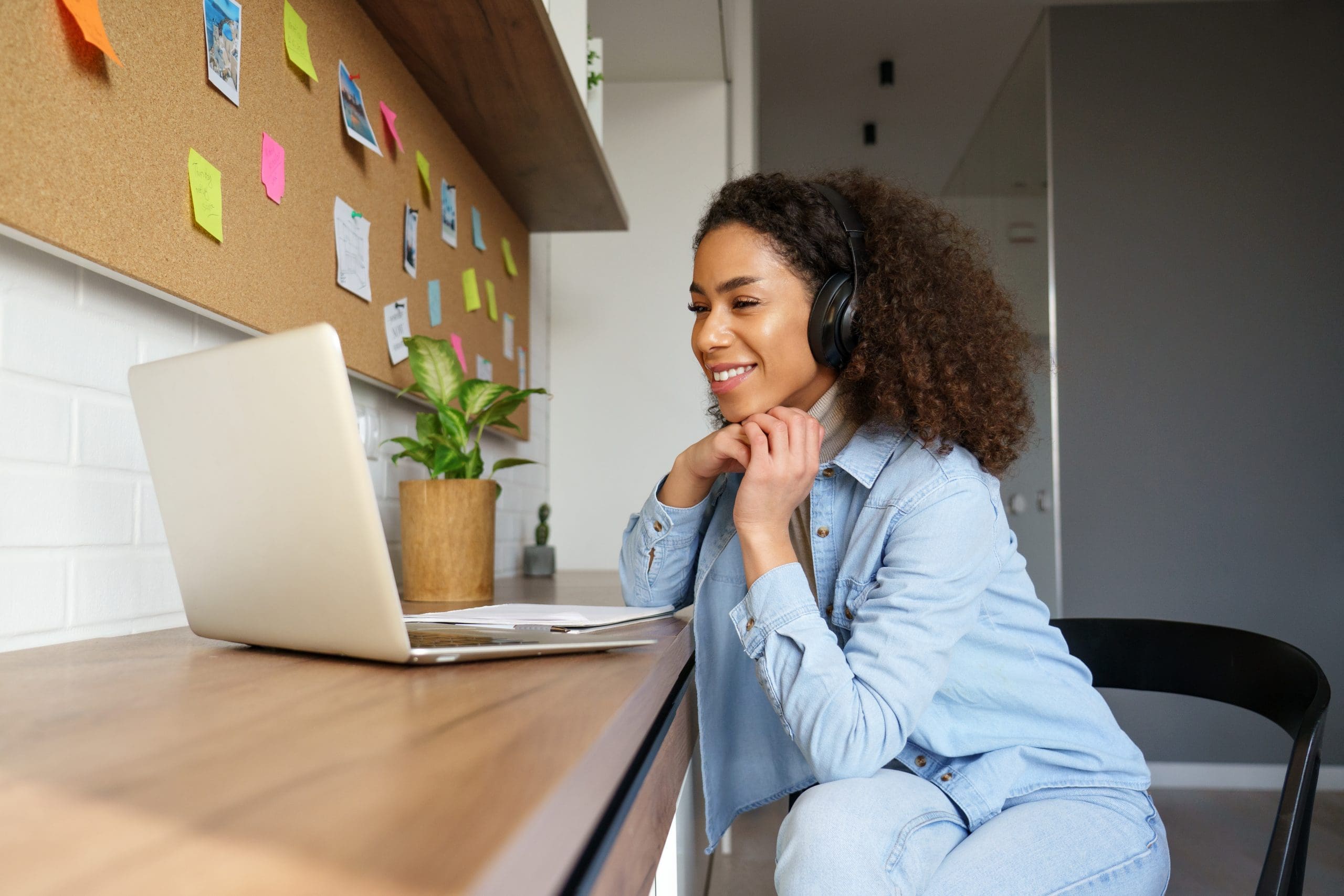 Smiling young african american teen girl wear headphones video calling on laptop. Happy mixed race pretty woman student looking at computer screen watching webinar or doing video chat by webcam.