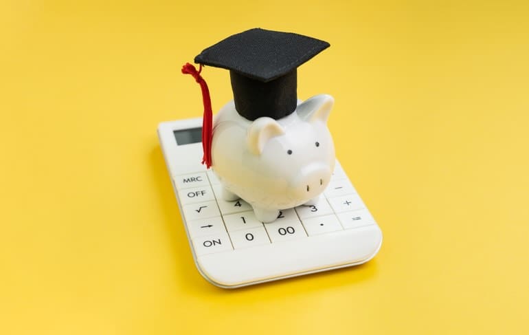 Piggy bank with graduation cap on a calculator